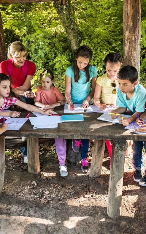 Kindergruppe an einem Holztisch draußen