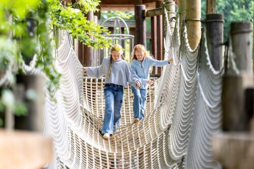 Zwei Mädchen auf einer aus Tauen geknüpften Brücke