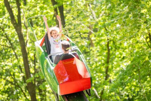 Zwei Kinder im zweisitzigen Butterflywaggon, der in einer U-förmigen Bahn auf und ab fährt
