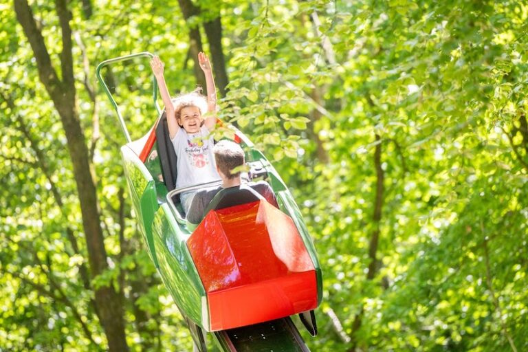 Zwei Kinder im zweisitzigen Butterflywaggon, der in einer U-förmigen Bahn auf und ab fährt
