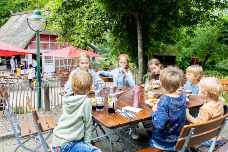 Gruppe von Kindern isst am Terrassentisch des Wildpark-Restaurants zu Mittag