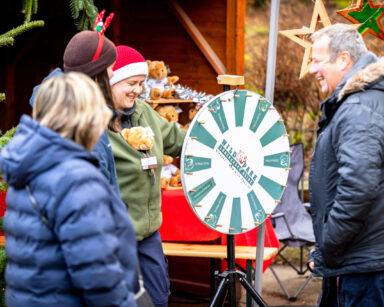 Leute auf dem Weihnachtsmarkt drehen am Glücksrad