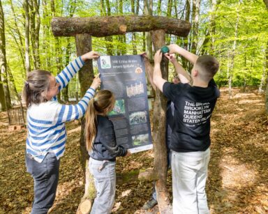 Eine der Infotafeln am Igelpfad wird von Kindern aufgehängt.