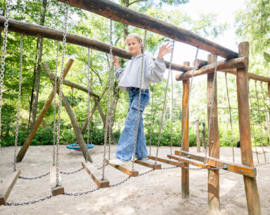 Mädchen läuft über Hängebrücke auf dem Spielplatz